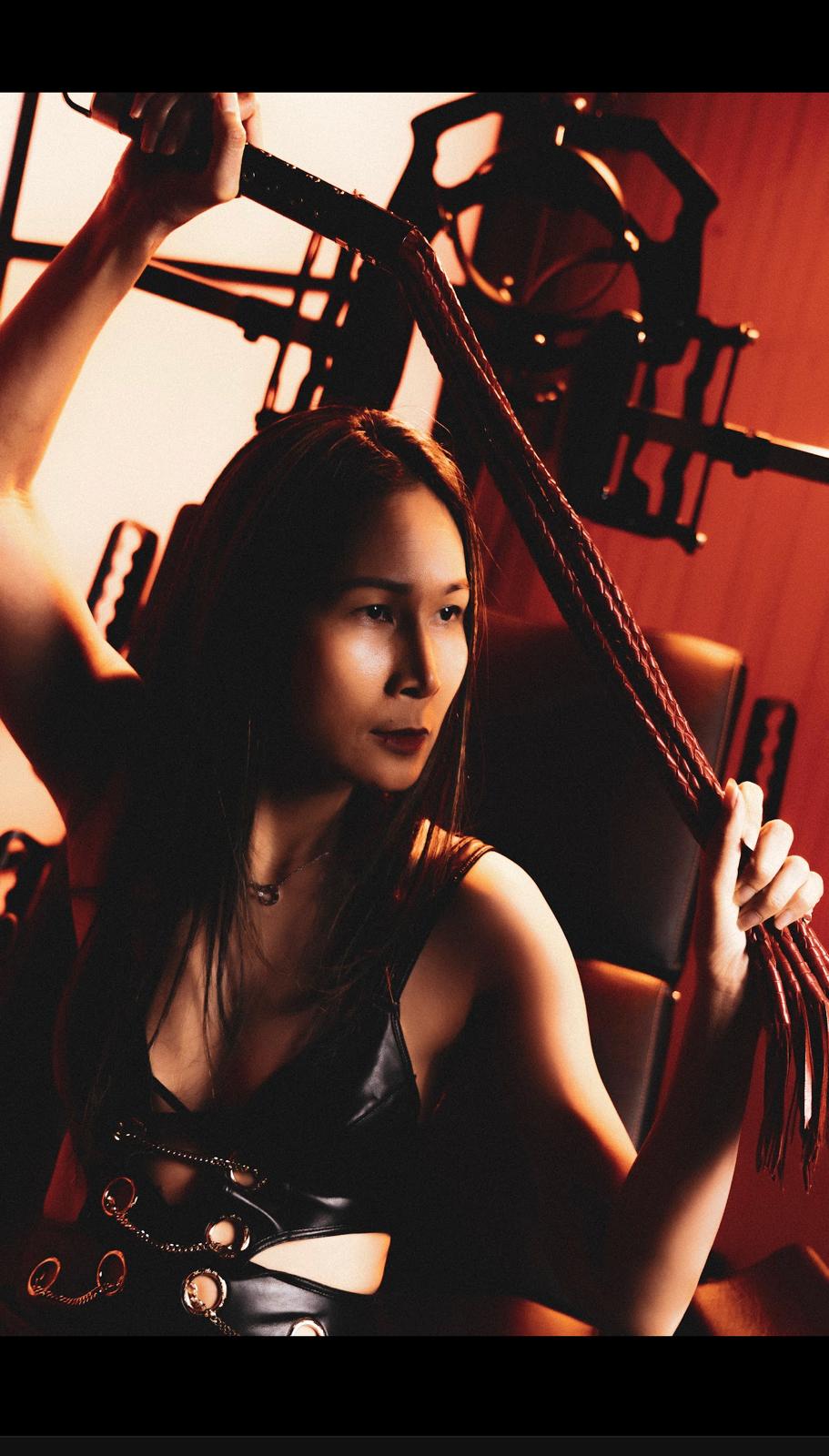Empress Nyx — in the chamber, flogger drawn, oxblood light
